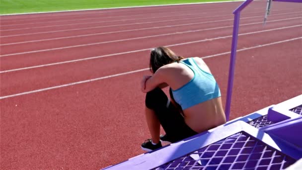 Desperate disappointed track runner athlete woman at a stadium, dolly — ストック動画