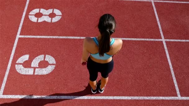 Nyomon követni a futó sportoló nő bemelegítés előtt futás-on egy stadion, felülnézet — Stock videók
