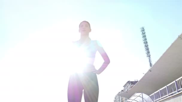 Камера слежения спортсменки бегущей по треку девушки бегущей на стадионе, солнечная вспышка, низкий угол — стоковое видео