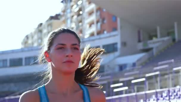 Tracking camera of a track runner athlete woman girl running at a stadium — Stockvideo