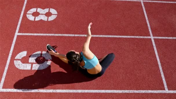 Lacak atlet pelari wanita pemanasan sebelum berjalan di stadion, top view — Stok Video