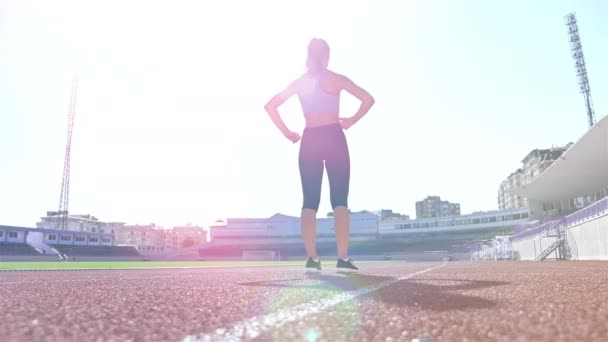 Бегунья спортсменка разогревается перед бегом на стадионе, солнечная вспышка — стоковое видео