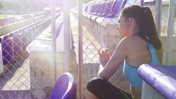 Desperate disappointed track runner athlete woman holding wire netting at stadium — Stock video