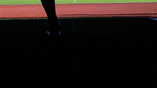 Läuferin kommt auf die Laufstrecke eines Stadions, wärmt sich auf, Beine nur — Stockvideo