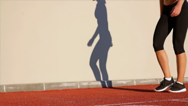 Pista mulher corredor e sua sombra em uma parede se preparando para correr — Vídeo de Stock