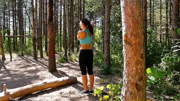 Seguimiento de la cámara de mujer niña calentando antes de correr trotando en el parque, madera, bosque, cámara lenta — Vídeos de Stock