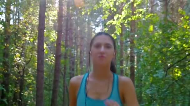 Tracking camera of woman girl with headphones running jogging in park, wood, forest, slow motion — Stock Video