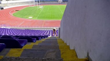 Bir stadyumda, yavaş merdivenlerden çalışan kadın kız atlet
