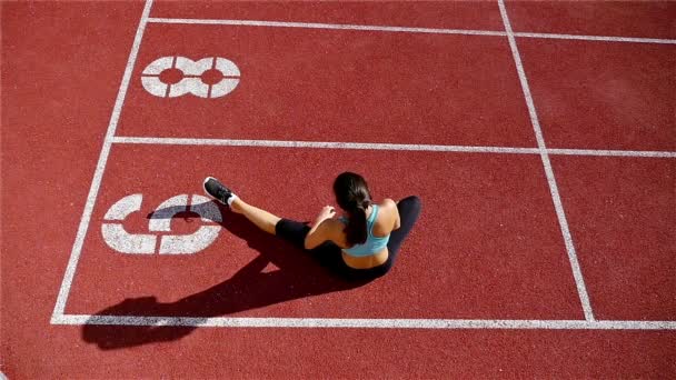 Baixo ângulo de pista atleta atleta mulher aquecendo antes de correr em um estádio, câmera lenta — Vídeo de Stock