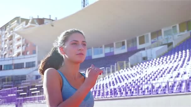 Cámara de seguimiento de una atleta corredor de pista chica corriendo en un estadio, cámara lenta — Vídeos de Stock