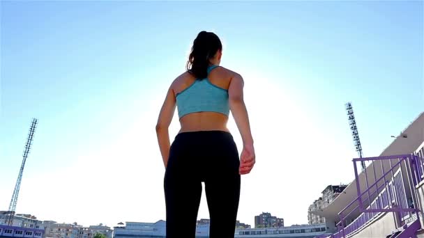 Κάμερα παρακολούθησης ενός κομματιού δρομέας κορίτσι γυναίκα αθλητής τρέχει σε ένα στάδιο, χαμηλή γωνία, ήλιος φωτοβολίδα, αργή κίνηση — Αρχείο Βίντεο