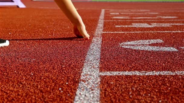 Track runner vrouw zetten haar handen op de startlijn, slow-motion — Stockvideo