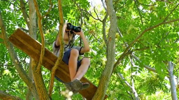 Rapaz a espiar com binóculos no topo da árvore — Vídeo de Stock