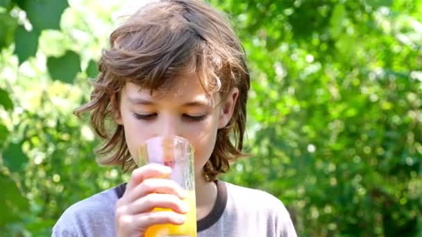O rapaz está a beber sumo de laranja lá fora. — Vídeo de Stock