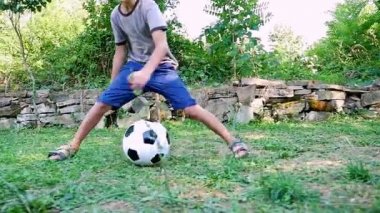 Ağır çekim genç çocuğun futbol topu eski bir evin avlusunda oynarken