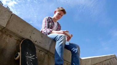 Genç çocuk yazılı SMS, mesaj smartphone cep telefonu ile mavi gökyüzü karşı düşük açılı görünüş