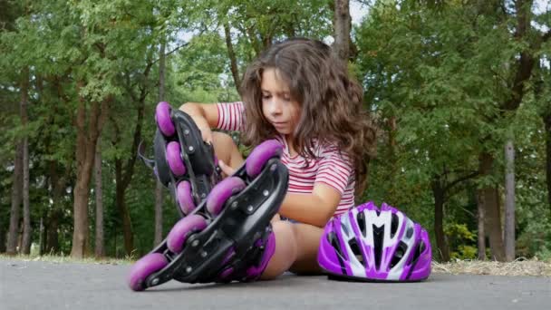 Petite fille mignonne mettant des rouleaux dans l'allée du parc — Video