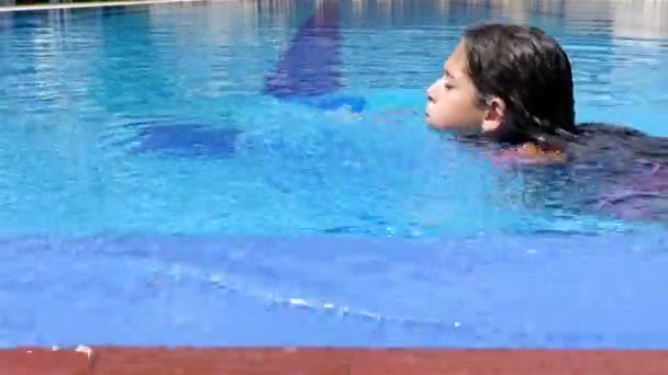 Милая маленькая девочка плавает в бассейне — стоковое видео