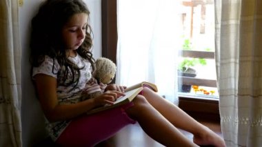 Onu ayı oyuncak kitap okuma eski bir ev, kenarında oturan sevimli küçük kız