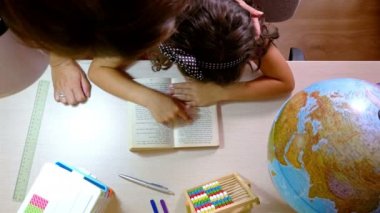 Küçük bir kızın masasına gelen anne adlı bir kitap okuma Üstten Görünüm
