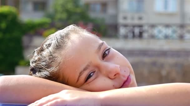 Retrato de una linda niña sonriendo en el borde de una piscina — Vídeos de Stock