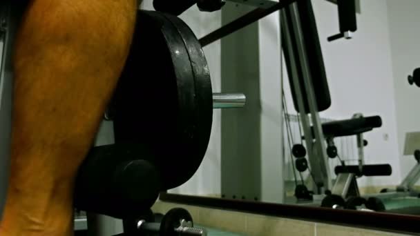 Чоловік тренується в спортзалі. Крупним планом чоловічі ноги тягнуть вагу машини — стокове відео