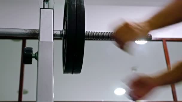 Athlete putting weights on barbell in fitness gym — Stock Video