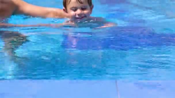 Liten pojke bada i en pool, hans pappa att hjälpa honom — Stockvideo