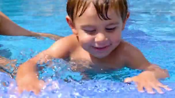 Kleiner Junge schwimmt in einem Pool, sein Vater hilft ihm — Stockvideo