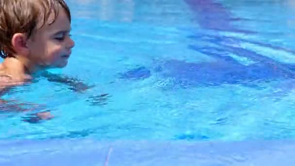 Un niño nadando en una piscina, su padre ayudándolo. — Vídeo de stock