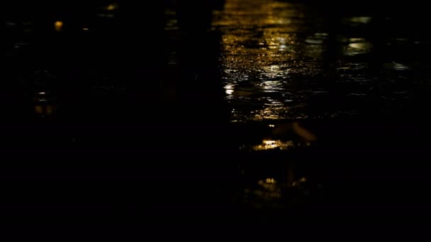 Close-up shot van licht regen op weg 's nachts, met voeten passerende — Stockvideo