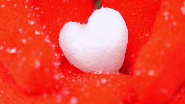 Las manos del niño en guantes rojos sosteniendo el corazón de la nieve mientras nieva, de cerca — Vídeo de stock