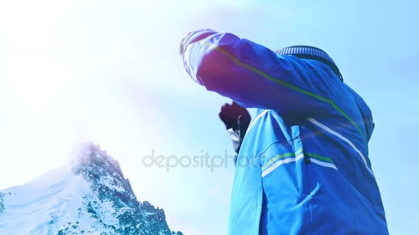 Visão de baixo ângulo do esquiador masculino colocando seus óculos no céu azul — Vídeo de Stock