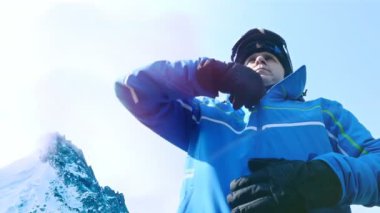 Erkek kayakçı mavi gökyüzü gözlüklerini koyarak düşük açılı görünümü