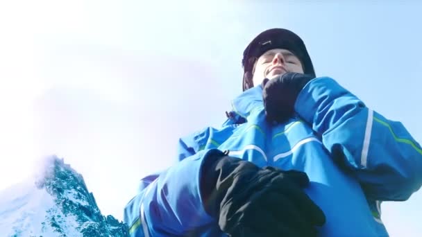 Visão de baixo ângulo do esquiador feminino colocando seus óculos no céu azul — Vídeo de Stock