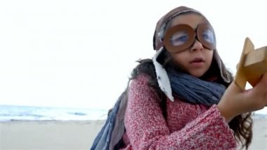 Pilot şapkası mavi gökyüzü, yavaş hareket karşı ahşap uçak ile oynarken küçük kız