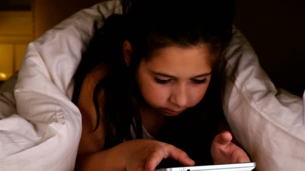 Niedliches kleines Mädchen mit Tablet-PC unter einer Decke in einem dunklen Raum. Geste der Verlorenheit. — Stockvideo