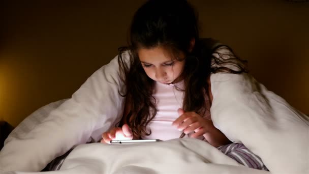 Söt liten flicka med TabletPC under filt i ett mörkt rum. Förlorande gest. — Stockvideo