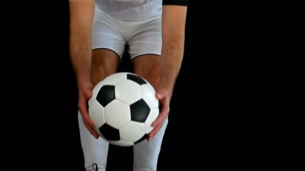 Fotbalista v botách uvedení nohu na míč, černé pozadí — Stock video