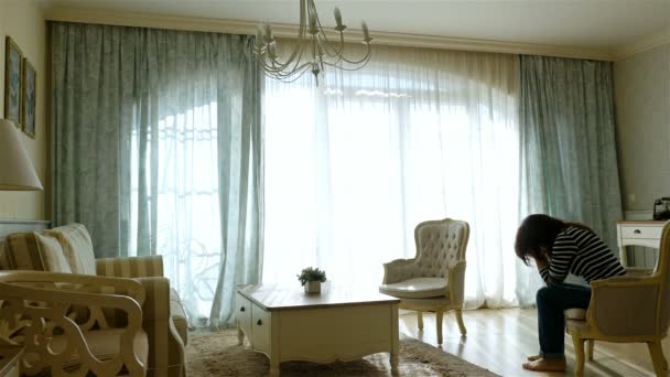 Mulher perturbada saindo e voltando ao longo da janela de um aconchegante apartamento — Vídeo de Stock