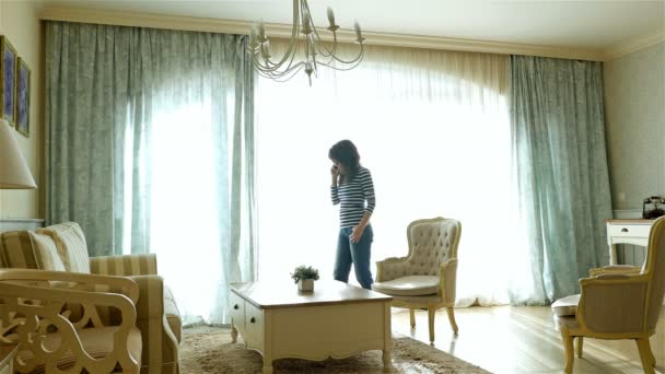 Upprörd kvinna gå fram och tillbaka längs fönstret i en mysig lägenhet — Stockvideo