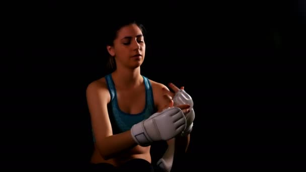 Jovem mulher exercitando boxe chutando treinamento ficando fora luvas no fundo preto — Vídeo de Stock