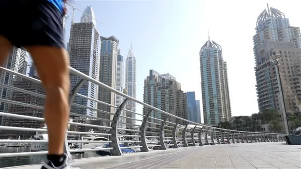 Lage hoekmening van atletische fitness man loopt in Dubai Marina joggen in de ochtend, slow-motion — Stockvideo