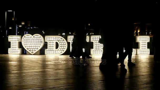 Geceleri, 4 k ışıklı "Dubai seviyorum" logosu önünde geçen insanlar — Stok video