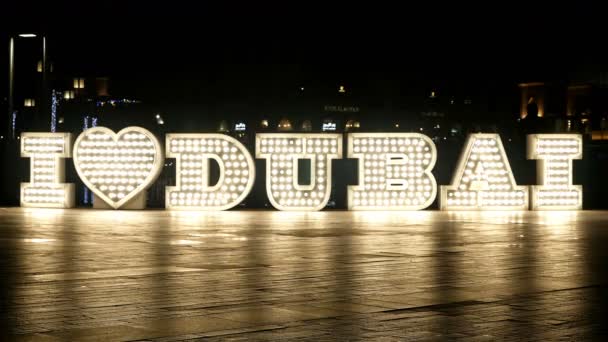 Passanten vor beleuchtetem "i love dubai" -Logo in der Nacht, 4k — Stockvideo