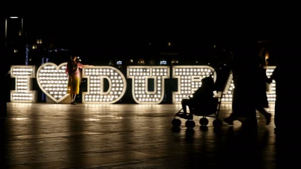 Voor de verlichte 'Ik hou van Dubai' logo's nachts, 4 k passerende mensen — Stockvideo