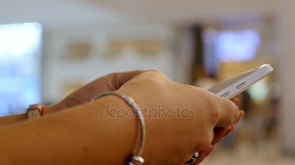 Mulher usando telefone inteligente no shopping, apenas mãos, pessoas desfocadas no fundo — Vídeo de Stock