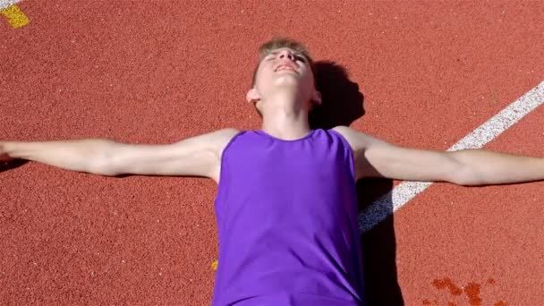 赛道赛跑男孩少年躺在疲惫疲惫的体育场轨道线 — 图库视频影像