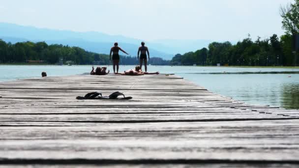 水着で日光浴や川の木製の桟橋で楽しみを持っている人 — ストック動画
