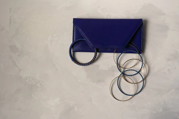 Clutch bag with bracelets on a gray background